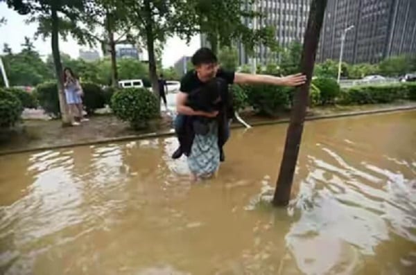 Chine: Elle porte son copain sur son dos pour traverser une rue inondée, sa raison est hilarante!