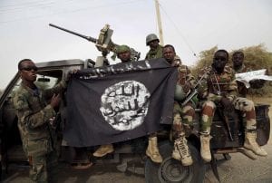 Nigerien soldiers hold up a Boko Haram flag that they had seized in the recently retaken town of Damasak, Nigeria, March 18, 2015. Chadian and Nigerien soldiers took the town from Boko Haram militants earlier this week. The Nigerian army said on Tuesday it had repelled Boko Haram from all but three local government districts in the northeast, claiming victory for its offensive against the Islamist insurgents less than two weeks before a presidential election. Picture taken March 18. REUTERS/Emmanuel Braun - RTR4TZO2