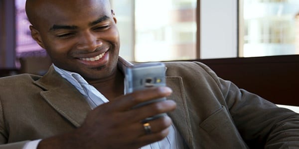 Young man looking at mobile phone, smiling, close-up