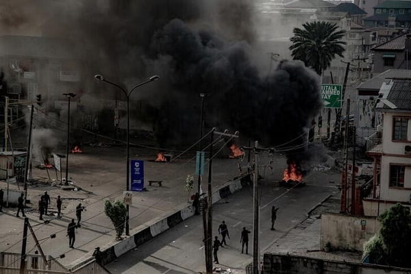 Armed men are seen near burning tires on the street, in Lagos