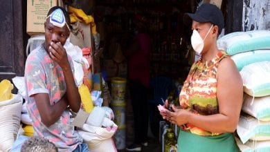 Traders wear protective masks at the Kimironko market as they wait for shoppers to stock up on essential items that have been price fixed in order to prevent exploitative prices in Kigali,