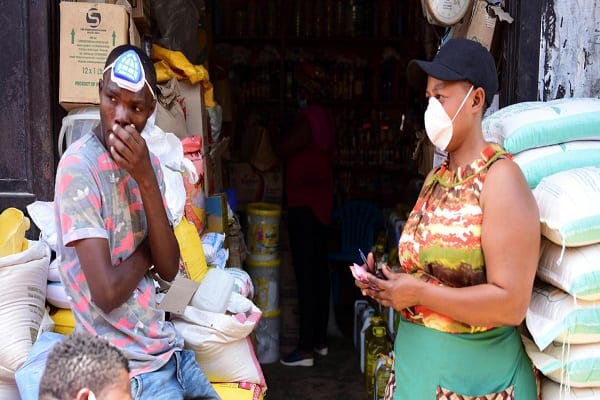 Traders wear protective masks at the Kimironko market as they wait for shoppers to stock up on essential items that have been price fixed in order to prevent exploitative prices in Kigali,