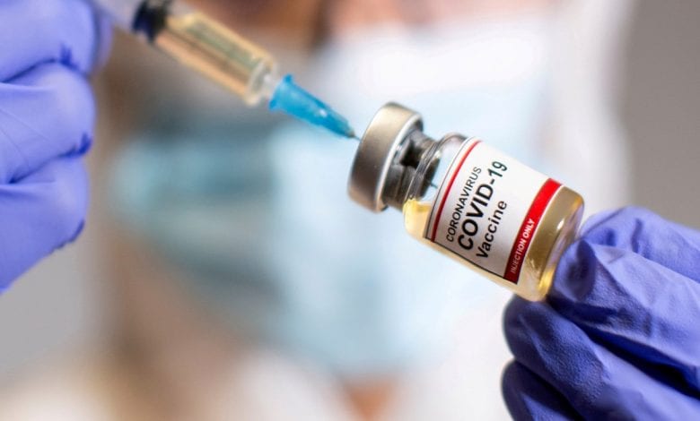 FILE PHOTO: A woman holds a medical syringe and a small bottle labeled “Coronavirus COVID-19 Vaccine