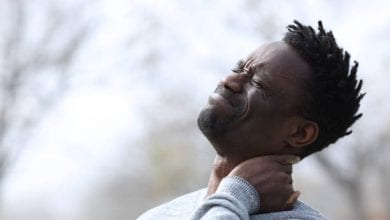 Black man suffering neck ache complaining outdoors