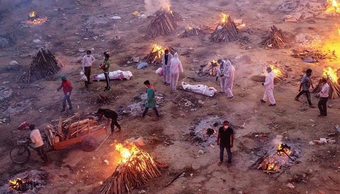 People wait to cremate COVID-19 victims at a crematorium ground in New Delhi