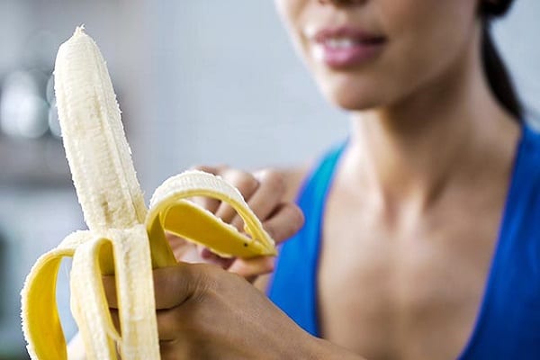 sports-woman-peeling-sweet-banana-for-snack-hungry-after-active-workout-in-gym