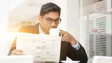 Business people drinking hot coffee and reading newspaper at caf
