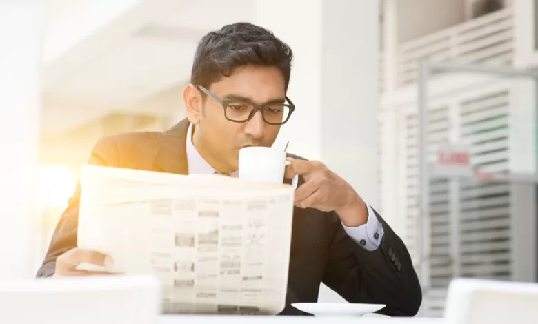 Business people drinking hot coffee and reading newspaper at caf