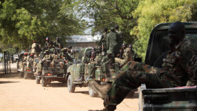 South Sudan army soldiers hold their weapons as they ride on a truck in Bor