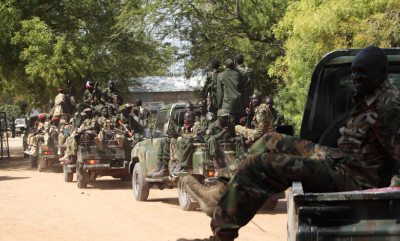 South Sudan army soldiers hold their weapons as they ride on a truck in Bor
