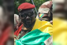 Mamadi Doumbouya portant un béret rouge et le drapeau guinéen