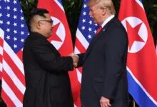 Donald Trump serrant la main de Kim Jong-un devant les drapeaux américain et nord-coréen