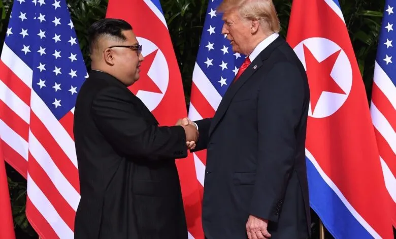Donald Trump serrant la main de Kim Jong-un devant les drapeaux américain et nord-coréen