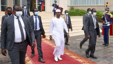 Mahamat Idriss Déby en boubou blanc, entouré de collaborateurs et de gardes lors d’une cérémonie au Tchad