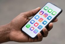 Main tenant un smartphone affichant des applications de réseaux sociaux