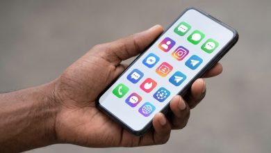Main tenant un smartphone affichant des applications de réseaux sociaux