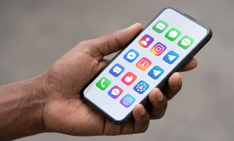 Main tenant un smartphone affichant des applications de réseaux sociaux